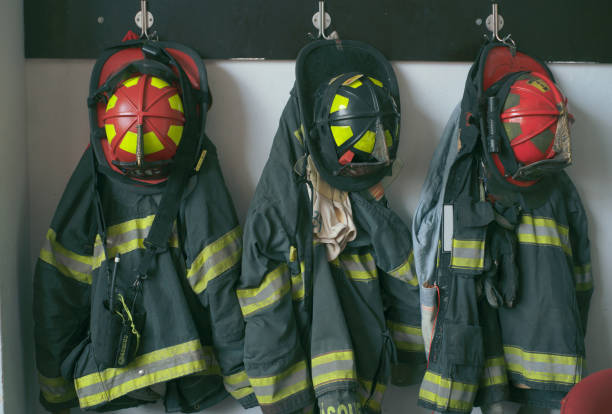 Firefighter uniforms and helmets hanging on a wall in a fire station